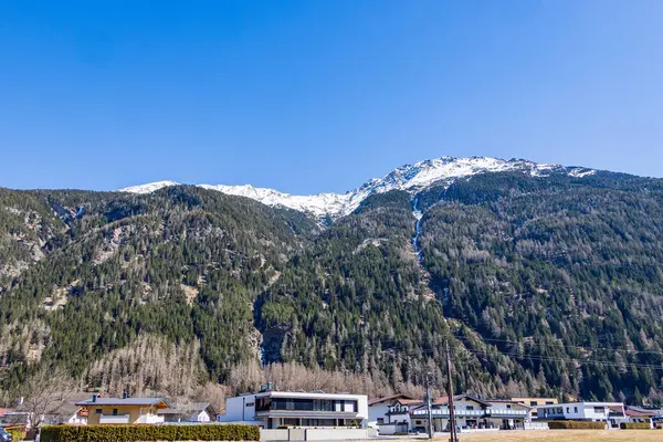Avusturya, Otztal 'da, yerleşim alanının üzerinde karla kaplı dağlık yamaçlar.