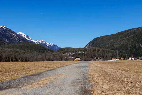 Karlı dağlık yamaçlar, açık bahar gökyüzü altındaki yerleşim evleri, Otztal, Avusturya