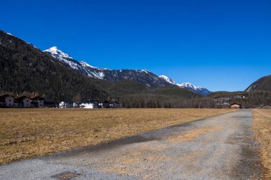 Karlı dağlık yamaçlar, açık bahar gökyüzü altındaki yerleşim evleri, Otztal, Avusturya