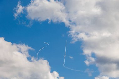 Beyaz bulutlu mavi gökyüzünde uçan uçakların beyaz izleri. 