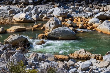 Renkli kayalarla dolu bir dağ deresi ve berrak akan bir su