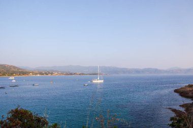 Tekneleri ve tepeleri olan körfez Korsika kıyıları