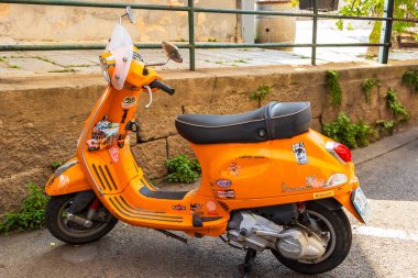 10 Haziran 2025 'te Fransa Korsika Ajaccio' da dar bir sokakta park etmiş eski turuncu Vespa scooter.