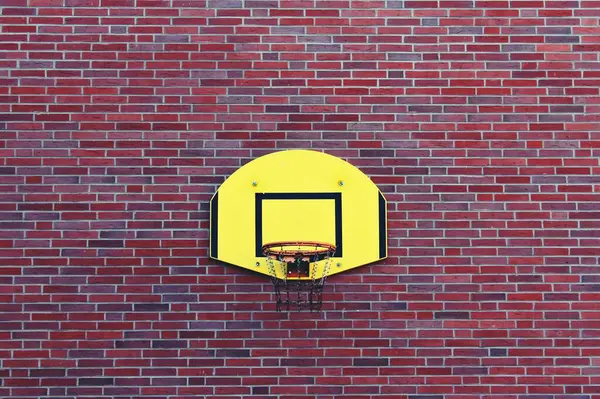 Tuğla binanın önündeki duvarda bir basketbol sahası