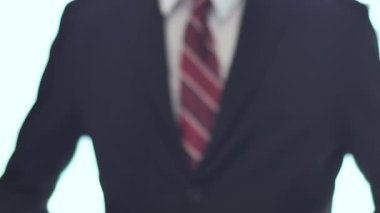 Bir adam ve bir kadının elleri kapalı çekimde sıkıca el sıkışıyor, takım elbiseli bir adam arka planda odak dışında ceketini ayarlıyor..