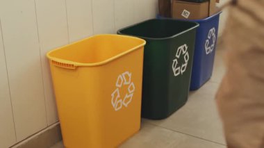 Plastik şişeleri uzaktan sarı bir geri dönüşüm kutusuna atan bir çocuğun üç kutu çerçeveli görüntüsü. Çevre dostu kampanyalar, geri dönüşüm eğitimi veya yeşil alışkanlıkları öğretmenin eğlenceli yollarını gösteren içerik için harika..