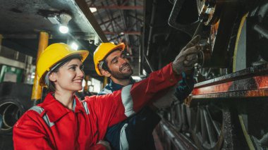 Kadın mühendis ve işçi tamir için fabrikada ekipman kontrol ediyorlar.