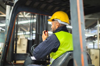 Forklift sürücüsü profesyonel kargo taşımacılığı iletişimi için radyodan konuşuyor.