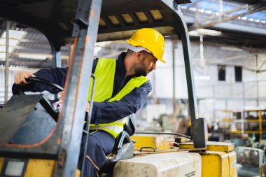 Depoda forklift kullanan miğfer takan işçiler
