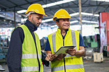 Fabrika istasyonundaki üretim işlemleri için tablet bilgisayar kullanan işçiler ve mühendisler