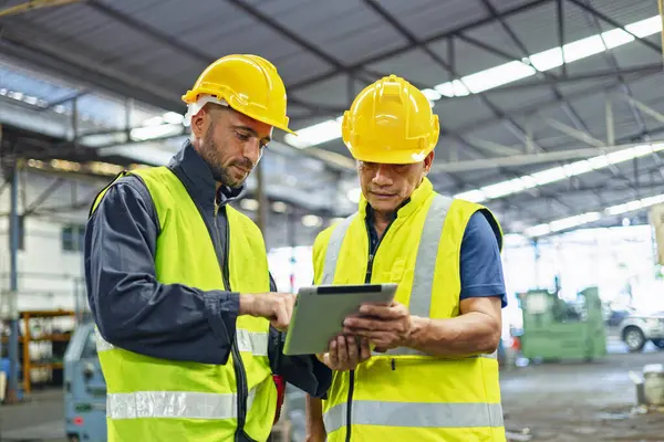 Fabrika istasyonundaki üretim işlemleri için tablet bilgisayar kullanan işçiler ve mühendisler