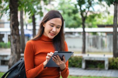 Gülümseyen üniversite öğrencisi, şehir merkezinde kitap tutuyor, güzellik ve güven saçıyor.