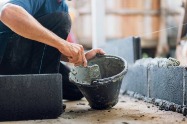 Adam yerde yatıyor ve çimento serpmek için mala kullanıyor.