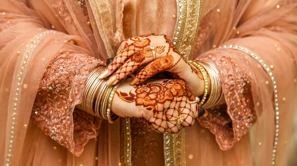 Beautiful Hands Of a Desi Bride with jewelry and Henna on it.