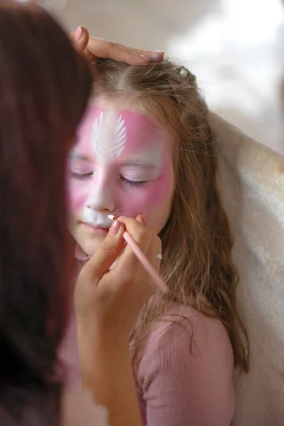 childrens makeup face paint drawings Girls face painting. Little girl having face painted on birthday party. closed eyes. High quality photo