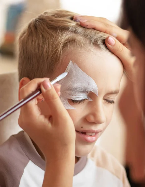 Master making aqua makeup on boys face. face painting kids. Child animator, artists hand draw face painting. High quality photo