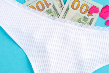 Dolar banknotları olan kadın külotu ve mavi arka planda kalpler. Para karşılığı seks arama kavramı. Yüksek kalite fotoğraf