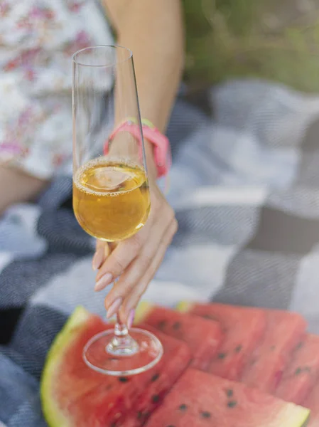 woman holding a glass of champagne. Summer picnic outdoors with blanket, eco style with fruits and wine. Romantic picnic . High quality photo