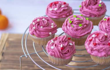 Kırmızı kremalı ve dekorlu kekler, inciler ve kırmızı ve yeşil yıldızlar. Tahta bir arka planda metal bir standın üzerinde tatil çörekleri. Yüksek kalite fotoğraf