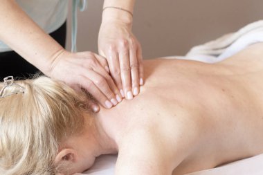 Sağlık salonundaki sırt masajı işlemi. Terapist elleri kadın vücudunda, yüzü olmayan insanlar, dikey görüntü, seçici odaklanma. Genç bir kadın kaplıca salonunda sırt masajı yaptırıyor. Güzellik tedavi konsepti