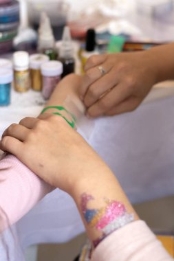 Seçici odaklanma. Çocuklar ve yetişkinler için dekoratif kozmetik. Kutsal Flash dövmesi. Çocuklar için dövme nakli. Usta bir kıza pullu temyporar simli dövme yaptırır. childreay. Canlandırıcılar