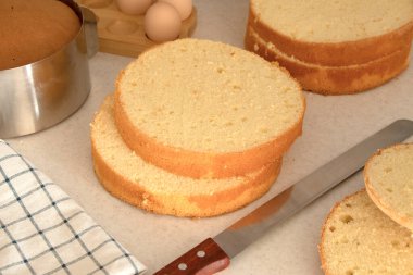Süngerli kek. Çörekler. Mutfakta bıçakla sünger keki ikiye böl. Vanilyalı pandispanya ya da şifonlu kek pişirmek, iki katlı dokuma. Ev yapımı aşçılık, tatlı. hazırlanma