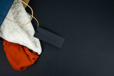 Noel Baba şapkası ve siyah arka planda yazı olmayan kağıt torba. Uzayı kopyala Noel satış kavramı.