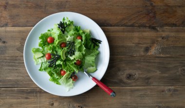 Beyaz tabak karışık salata, yosun, domates, marul ve avokado. Ahşap arka. Uzayı kopyala Üst görünüm.