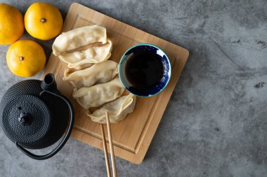 Asian food. Dim sum with soy sauce on bamboo board decorated with oranges and teapot. Copy space. Top view.