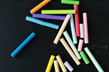 Siyah arka planda renkli tebeşirler. Sınıfa dönün. Uzayı kopyala Üst görünüm.