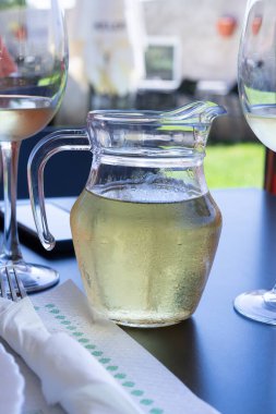 Masada iki şarap kadehinin yanında bir sürahi beyaz şarap var. Sürahinin içi buz dolu ve bardakların yarısı dolu. Sahne, sürahiyle rahat ve rahat bir atmosferde geçiyor. Şarablı sürahi..