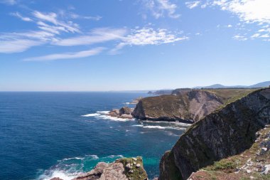 Kayalıkları olan kıyı manzarası ve bulutlu mavi gökyüzü. Cudillero 'daki Asturias Sahili.