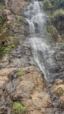 Resimde bir şelale gösteriliyor, su bir uçurumun kenarından aşağı akıyor. Sahne sakin ve huzurlu, suyun sesi rahatlatıcı bir atmosfer yaratıyor.