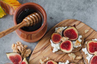 Tahta ve bir kavanoz bal ile bir tabak meyve. Sahne sıcak ve davetkar, bal ve meyve bir rahatlık ve hoşgörü hissi yaratıyor.