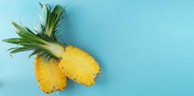 Mavi arka planda iki adet olgun ananas kesimi.