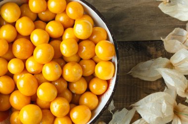 Altın böğürtlenli ve kuru yapraklı bir kase. Physalis peruviana
