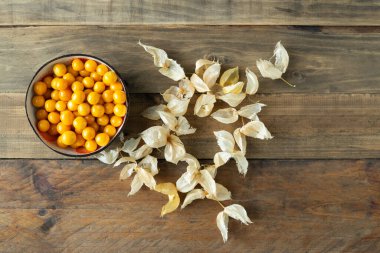 Masanın üzerinde birkaç yaprak olan bir kase altın çilek. Physalis peruviana