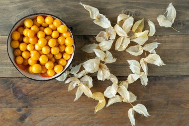 Masanın üzerinde birkaç yaprak olan bir kase altın çilek. Physalis peruviana