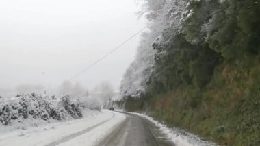 Üzerinde kablo olan karlı bir yol. Yol karla kaplı ve gökyüzü bulutlu.