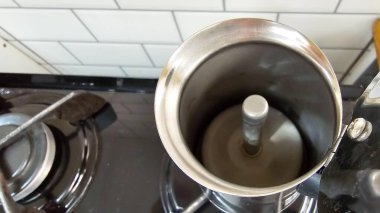 Kahvenin kaynatıldığı alüminyum kahve makinesinin iç kısmı. Çelik kahve makinesi, siyah bir sobanın üstünde.. 