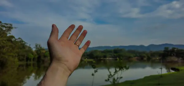 Şafak vakti el kaldırarak doğal manzaraya doğru yükseldi. Özgürlüğün jesti ve doğanın takdir edilmesi. Arka planda ağaçlar ve dağlar olan bitki örtüsü.
