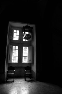 Mafra, Lisbon, Portugal- January 17, 2023: Chairs next to big wooden window of the Palace- Convent of Mafra. Monochrome picture