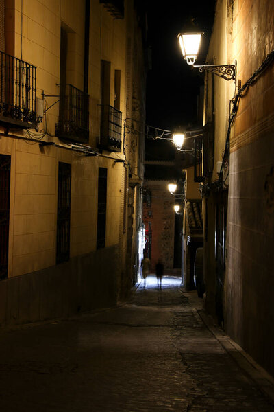 Narrow streets and Facades of historic houses at night in the old town of Toledo , Spain