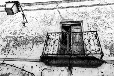 Zarar görmüş demir balkon ve klasik sokak lambasıyla ön cephe
