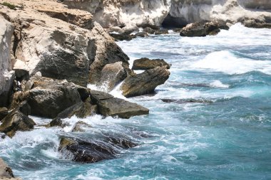 Dalgalar Los Escullos Beach, Almeria, Cabo de Gata sahillerine renkli kayaları çarpıyor.