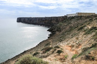 Kayalıklar ve Sagres kıyıları ve arka planda Sagres Kalesi