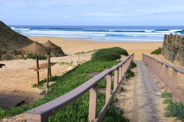 Portekiz, Algarve 'deki Castelejo Sahili' ne saman şemsiyeler ve ahşap geçitler.