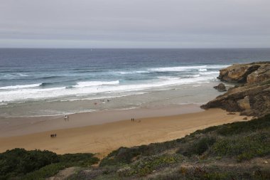 Güzel Monte Clerigo Sahili Algarve 'de bulutlu bir günde kaya oluşumlarıyla