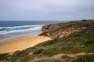 Güzel Monte Clerigo Sahili Algarve 'de bulutlu bir günde kaya oluşumlarıyla