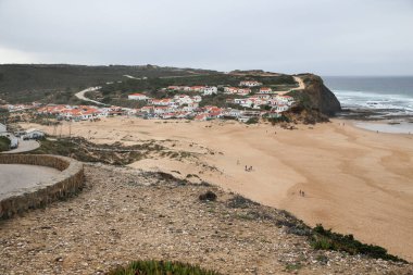 Güzel Monte Clerigo Sahili ve Aljezur kasabası bulutlu bir günde arka planda